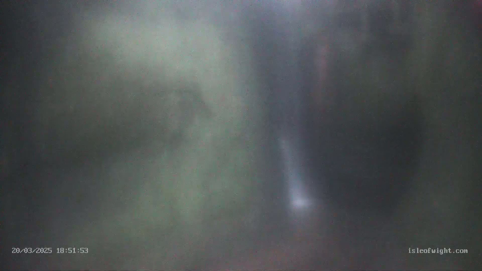 A blurry, dark image shows an indistinct, possibly wooded area in foggy or misty conditions.