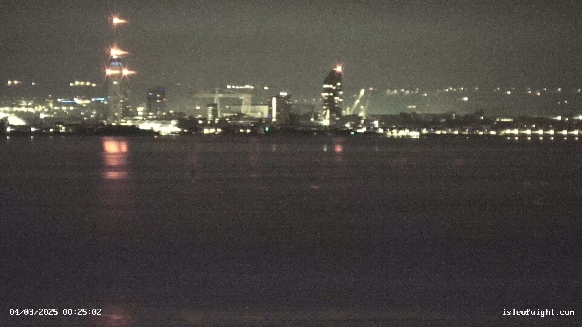 A nighttime view of a city skyline across a body of dark water.