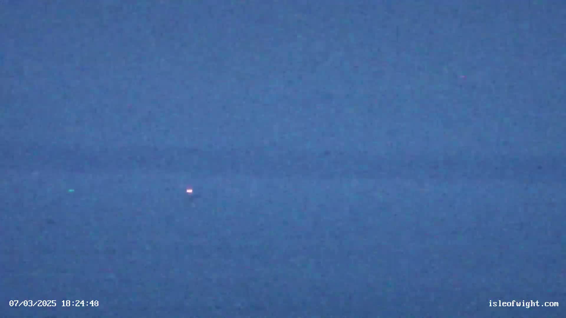 A dark blue expanse shows two faint lights in the distance under a twilight sky.