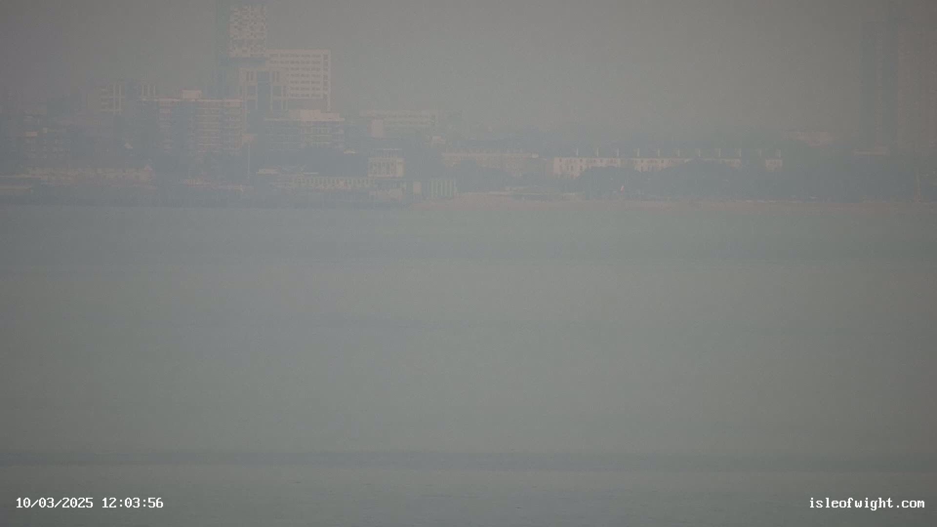 A hazy view of a city skyline across a body of water.