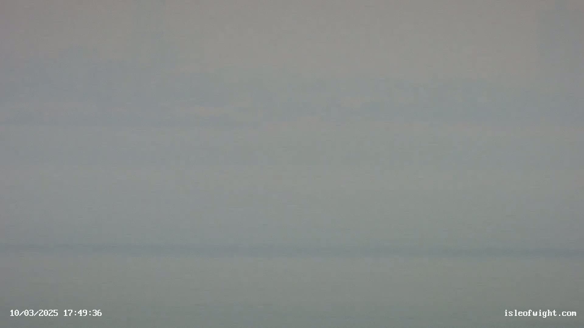 A hazy, overcast sky over a calm body of water.