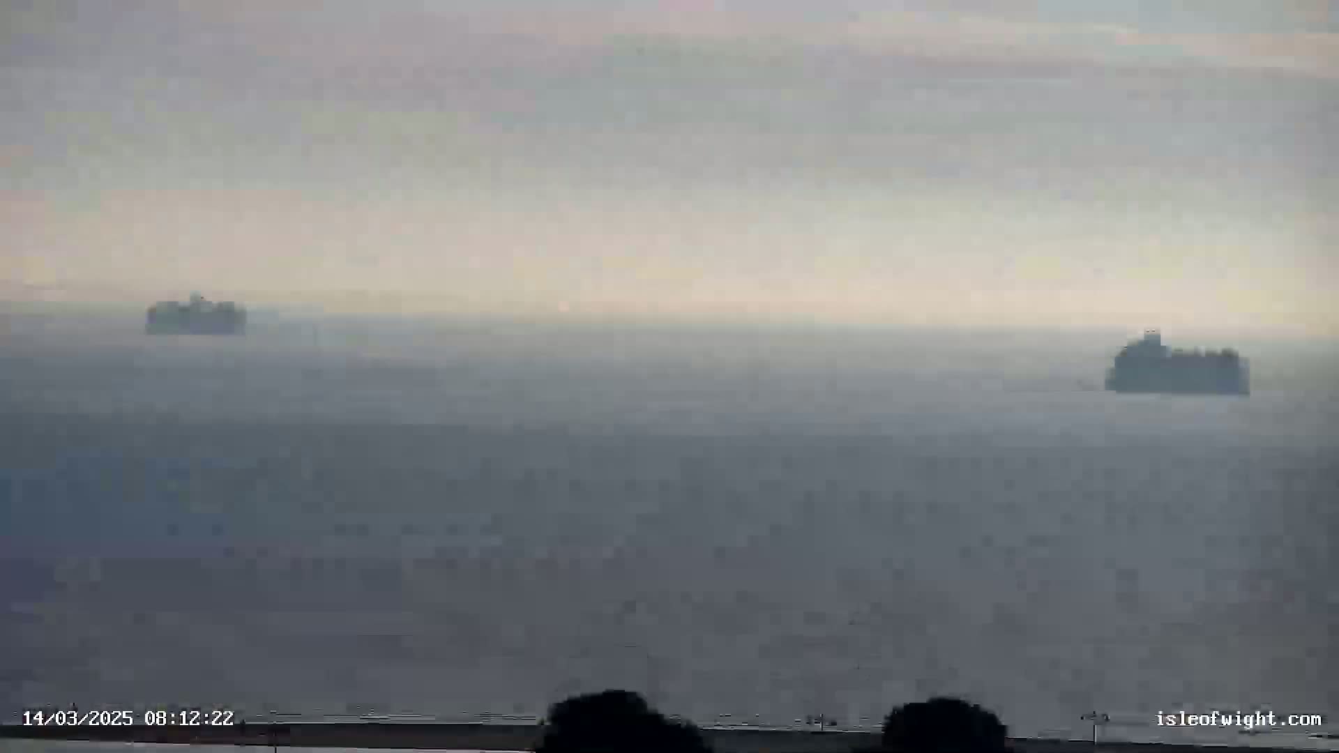 Two ships are visible on a hazy, gray sea.