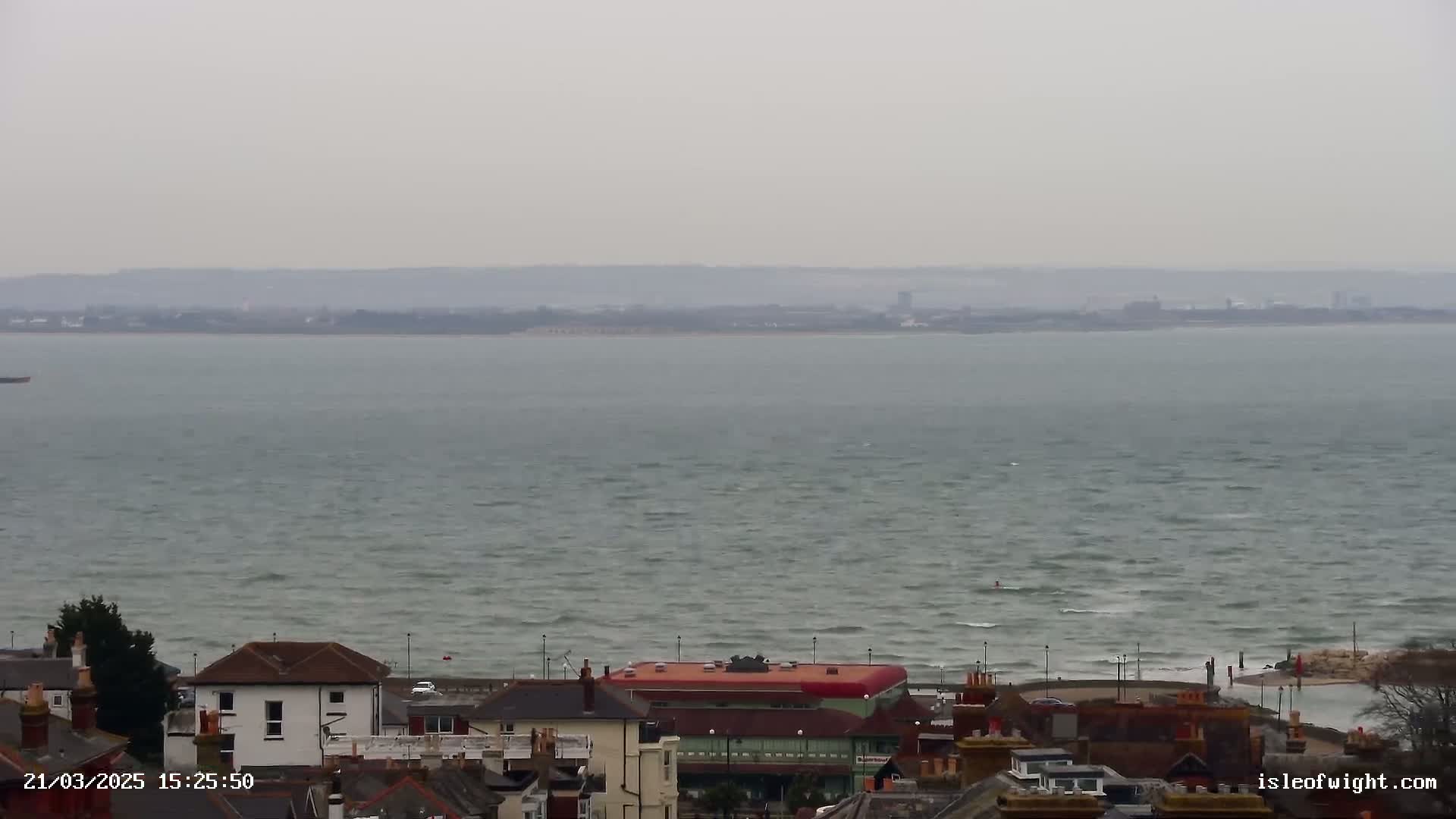 A coastal town overlooks a choppy, gray sea under an overcast sky.