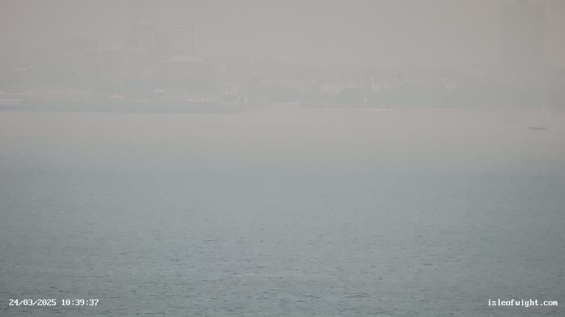 A hazy view shows a distant, indistinct shoreline across a calm body of water.