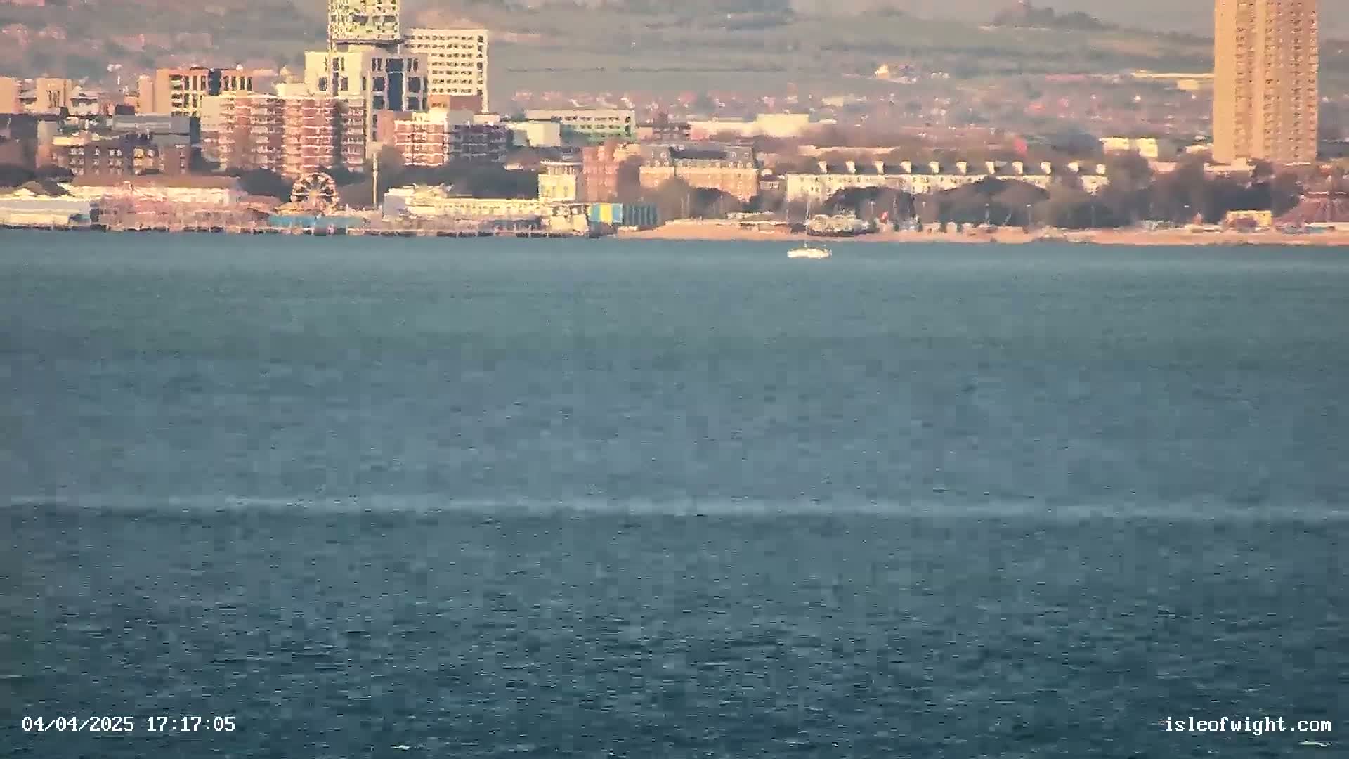 A body of water shows a distant cityscape under a partly cloudy sky.
