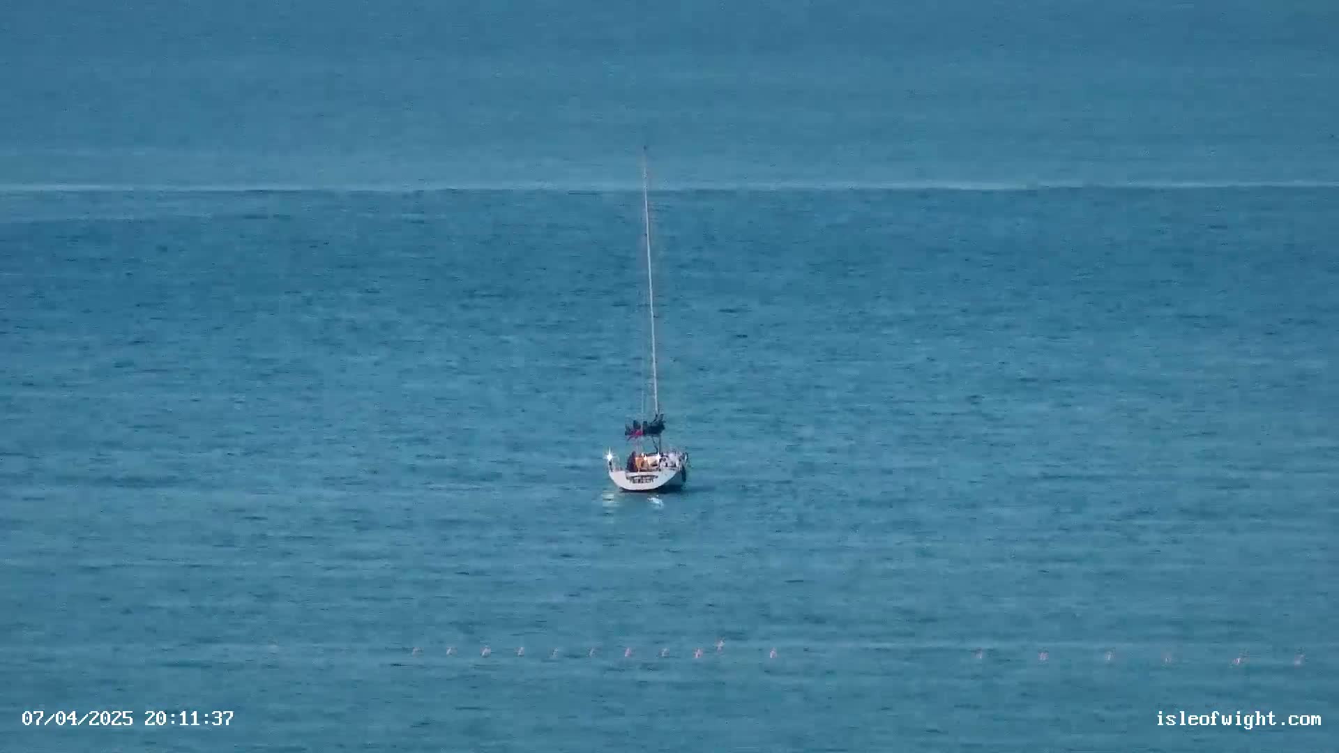 A sailboat is anchored in calm, blue water.
