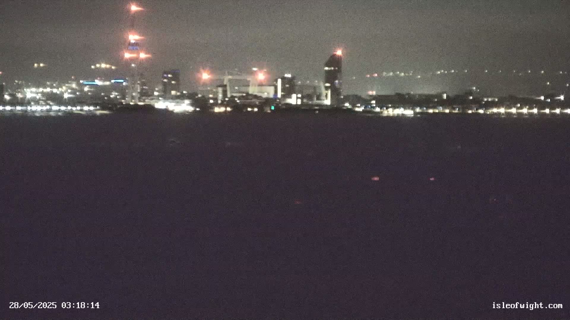 A nighttime view of a city skyline across a dark body of water.
