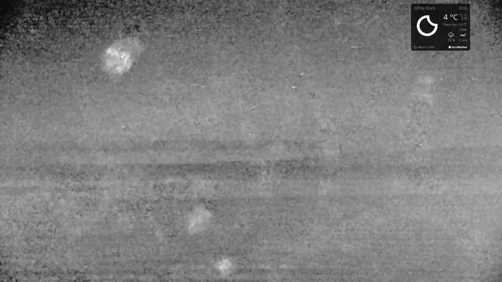 A nighttime, thermal image shows a clear sky with a few bright spots, and a dark, textured landscape.