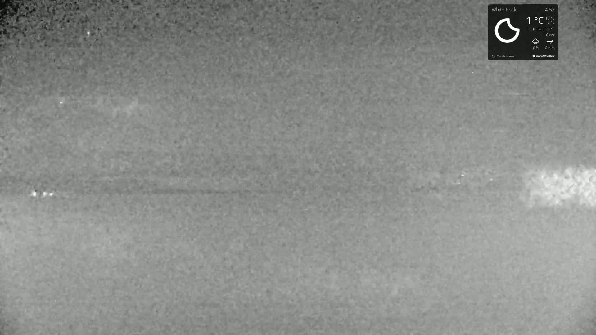 A grainy, low-light image shows a dark, mostly featureless landscape under a clear night sky.