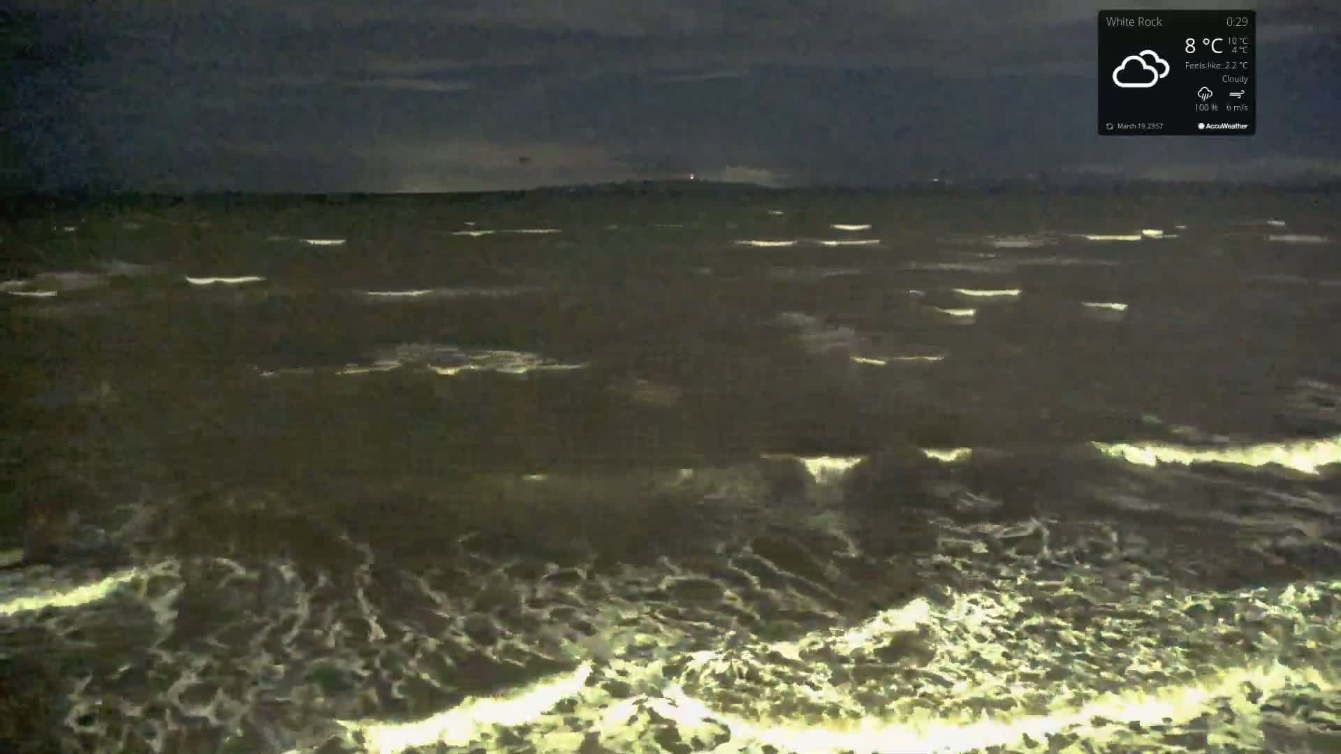 A dark, cloudy night shows a choppy sea with small waves.