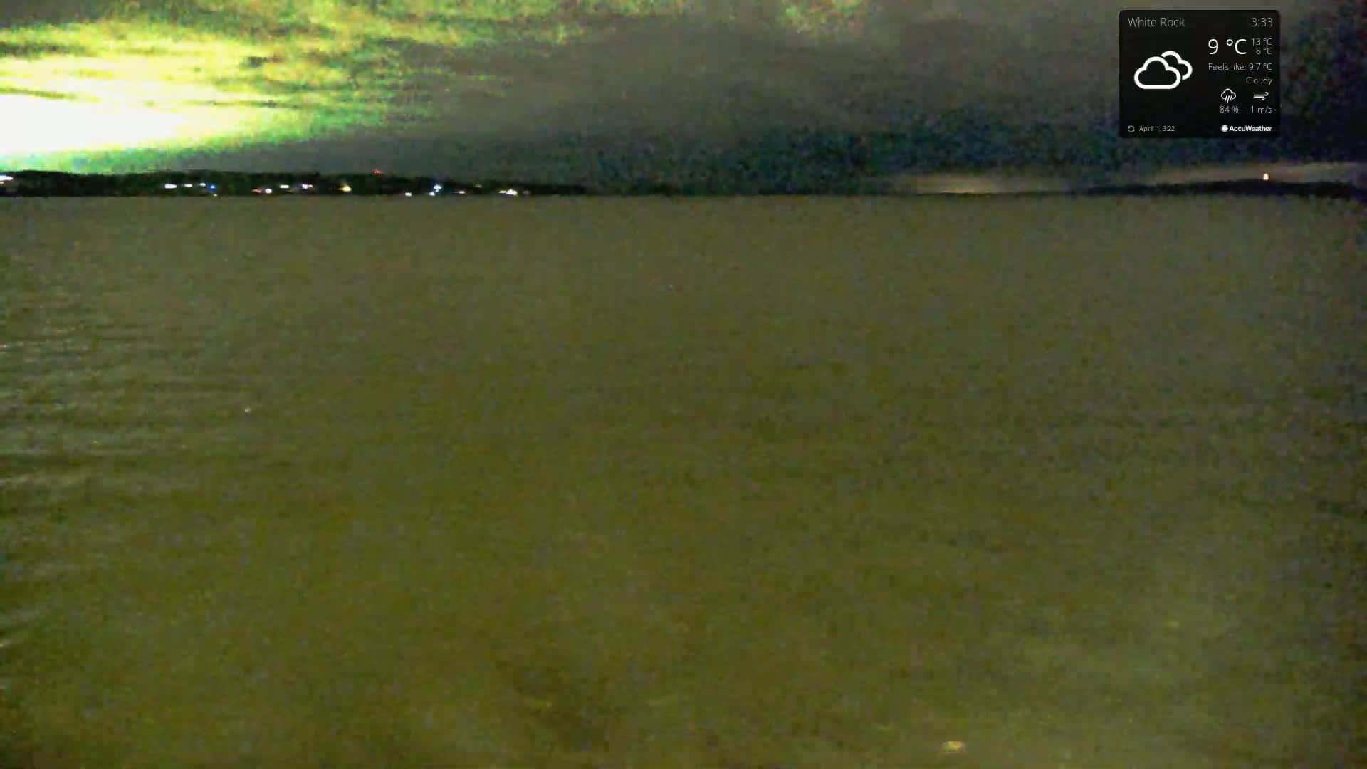 A dark, cloudy night scene shows a calm body of water under a yellowish-green sky.