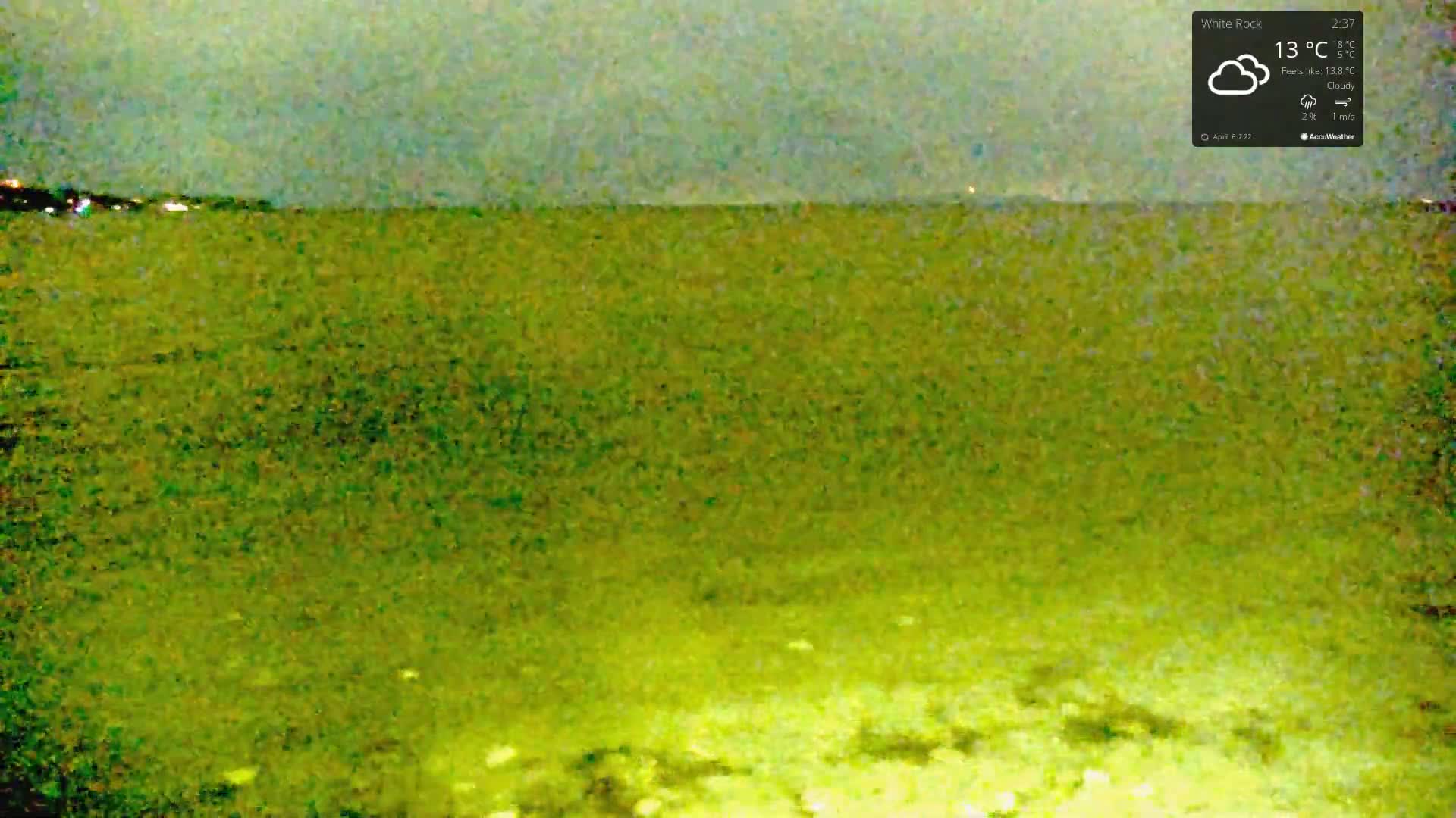 A cloudy night scene shows a body of water with a distant, dimly lit shoreline.