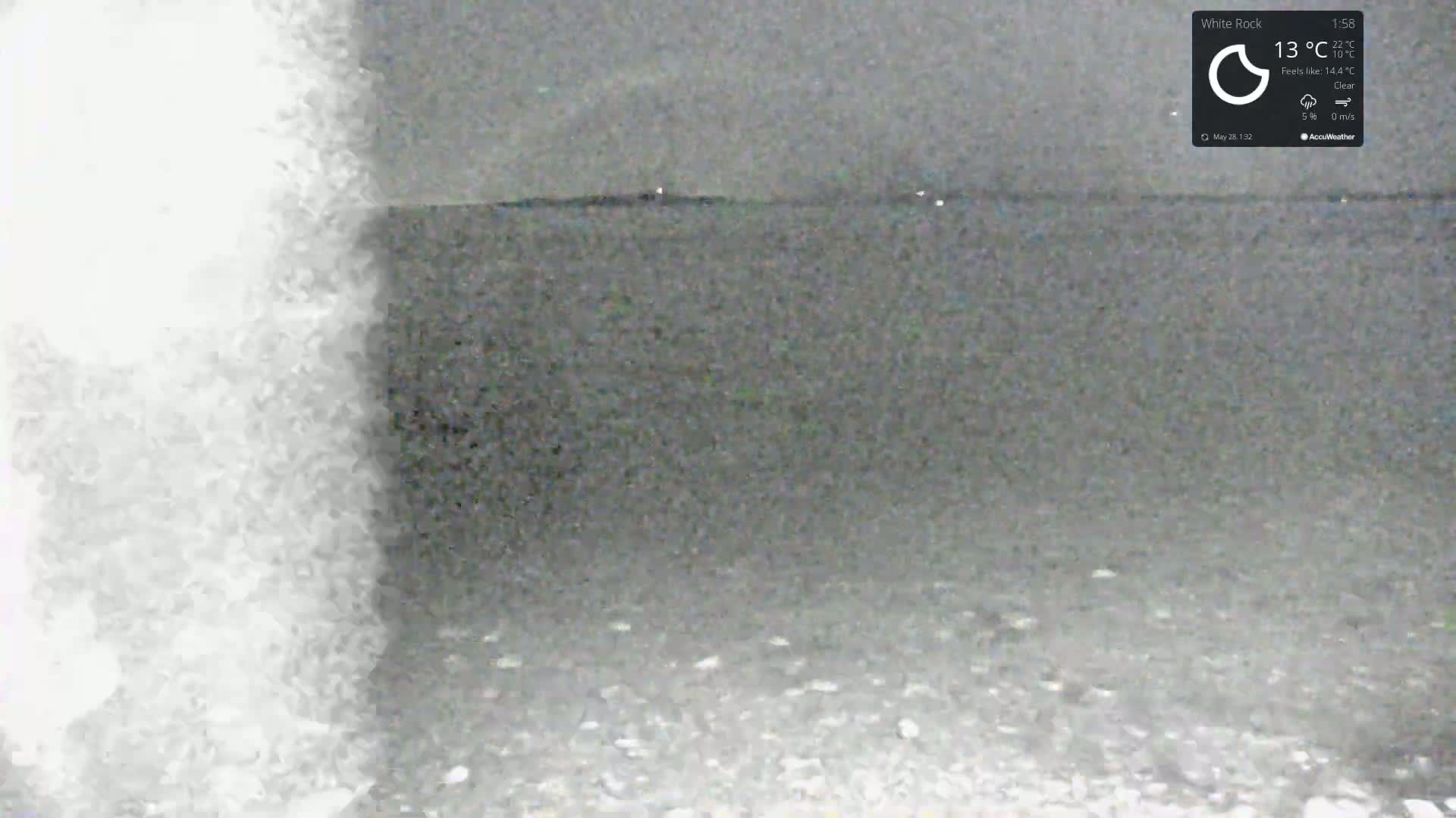 A blurry, grainy image shows a dark, gravelly ground extending to a dark horizon under a clear sky.
