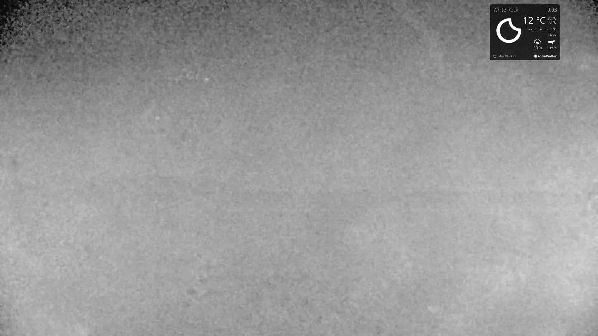 A grainy, grey image shows a clear, outdoor scene under a 12°C temperature with a 1 m/s wind.