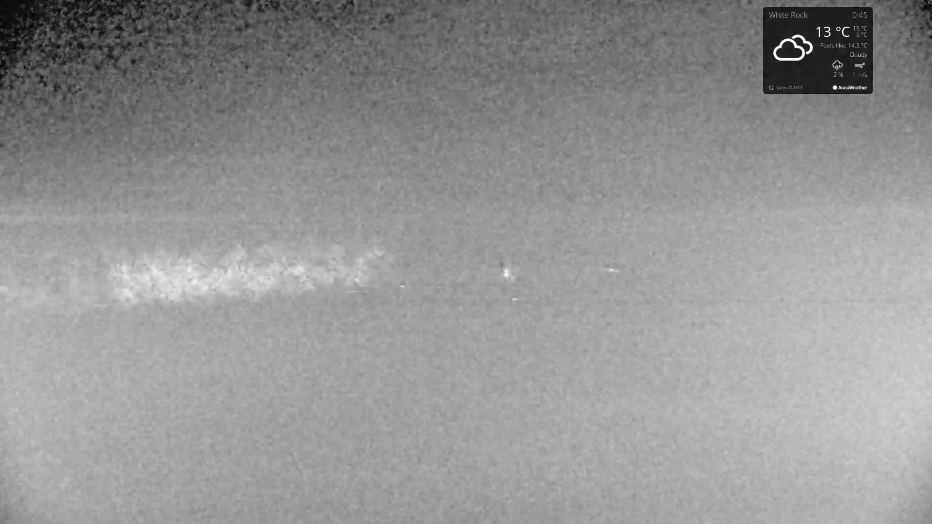 A grainy, low-light image shows a cloudy outdoor scene with a faint, horizontal line in the mid-ground.