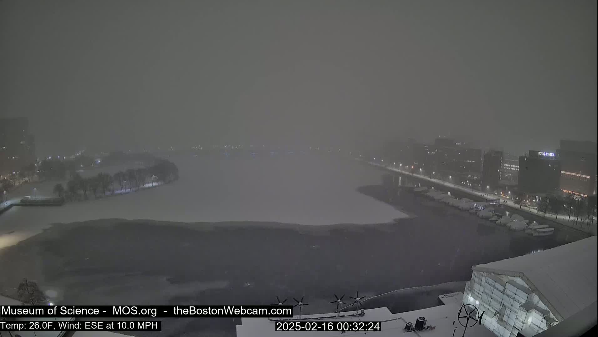 A snow-covered waterfront scene is visible under a heavy snowstorm with a 10 mph wind from the east-southeast.