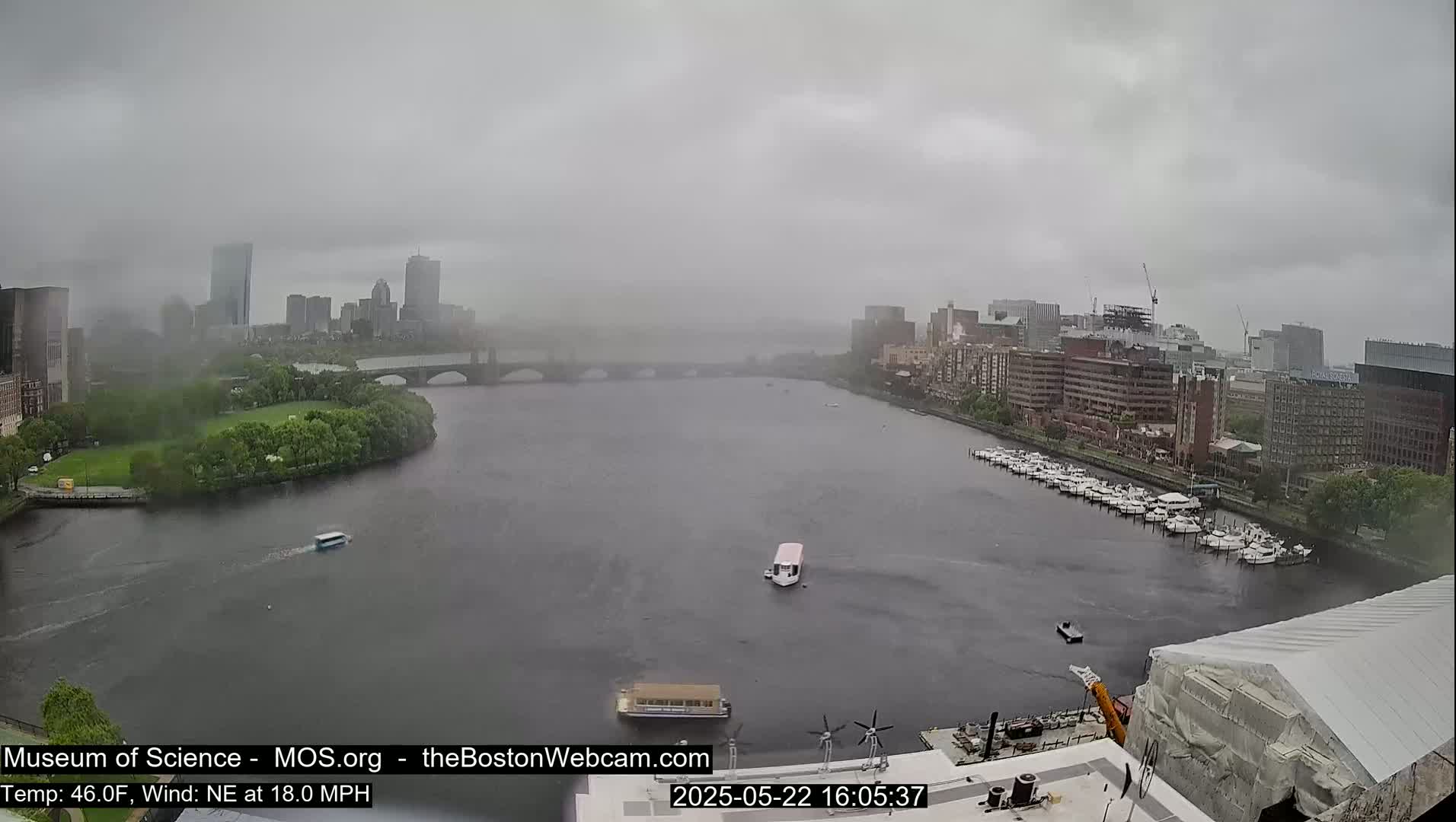 A wide shot of a city skyline across a river on a foggy day with a northeast wind.