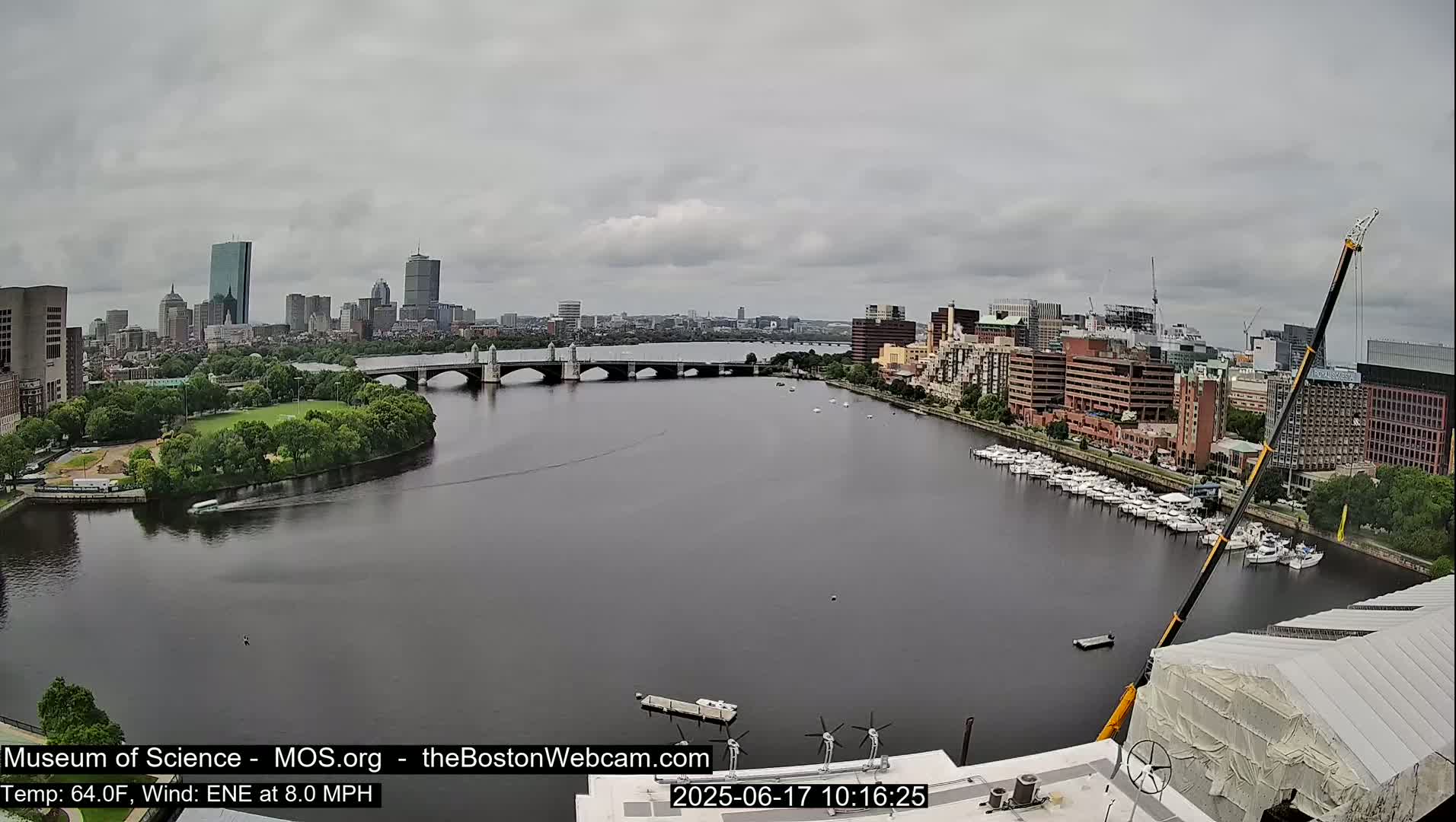 A city skyline with a bridge over a river on an overcast day, viewed from a high vantage point with a large crane visible in the foreground.