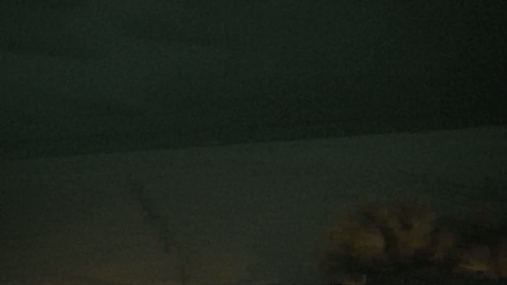 A dark, possibly nighttime scene shows faint plumes of smoke or dust rising from the lower portion of the frame.