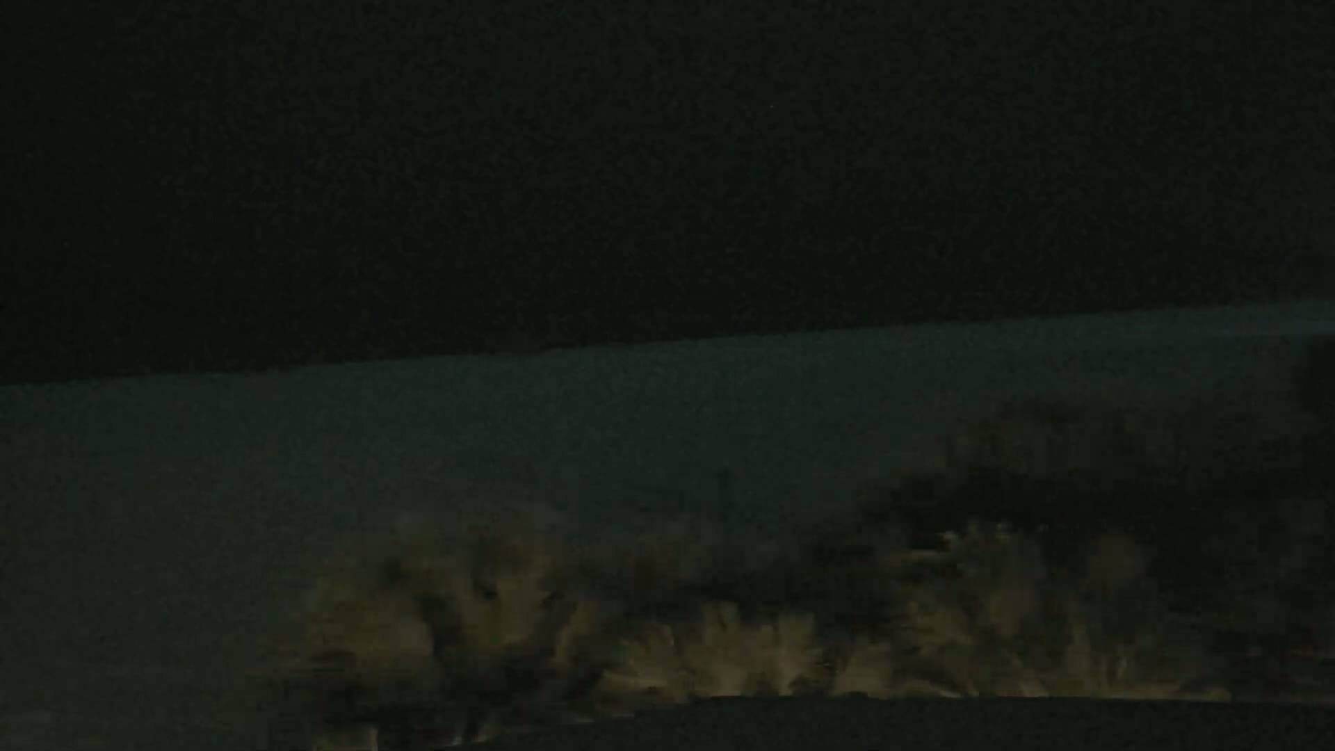 A low-light image shows a mass of light-colored, indistinct shapes at the bottom, possibly animals or objects, against a dark background.