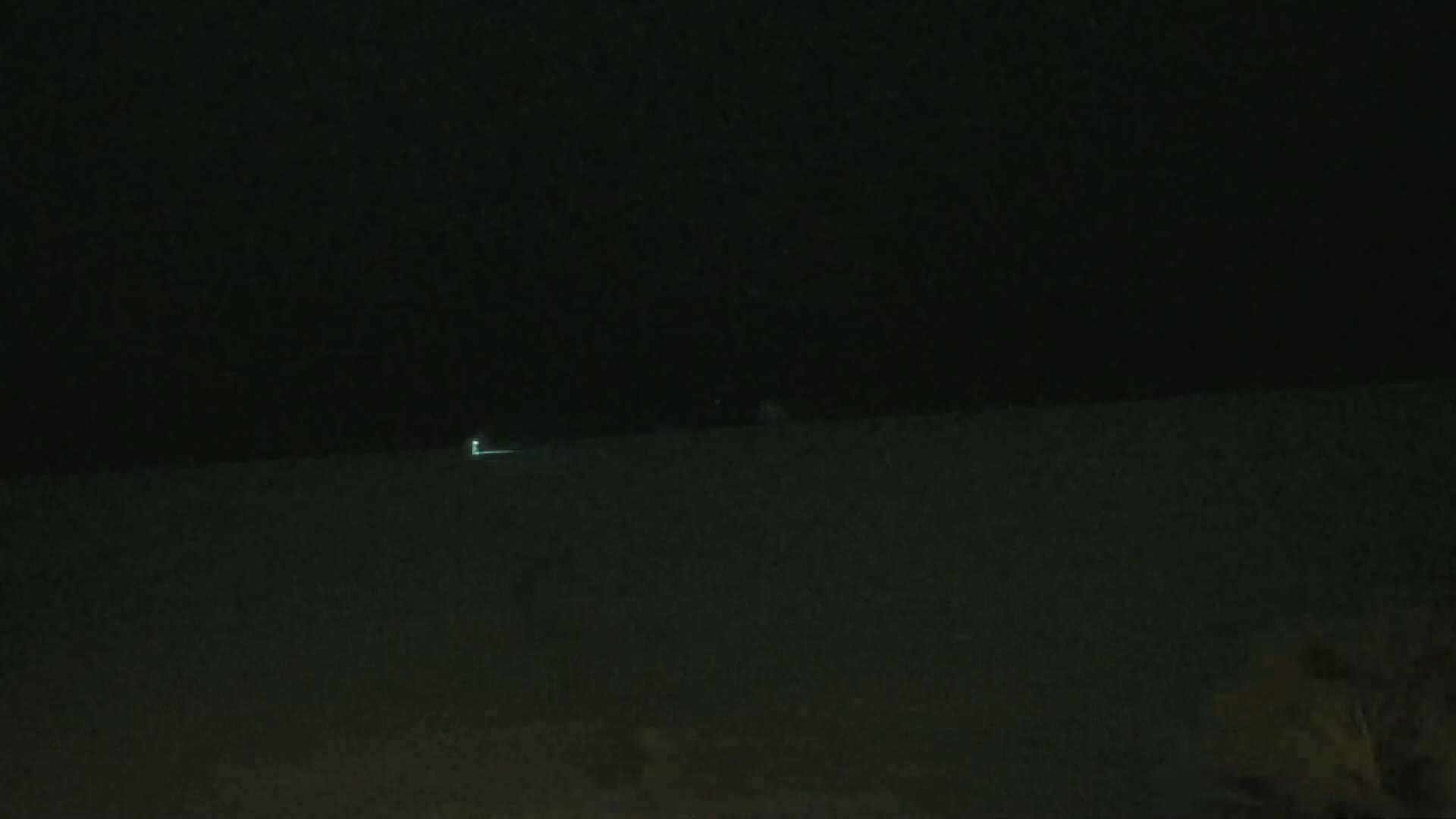 A faint light is visible on a dark, nighttime horizon.