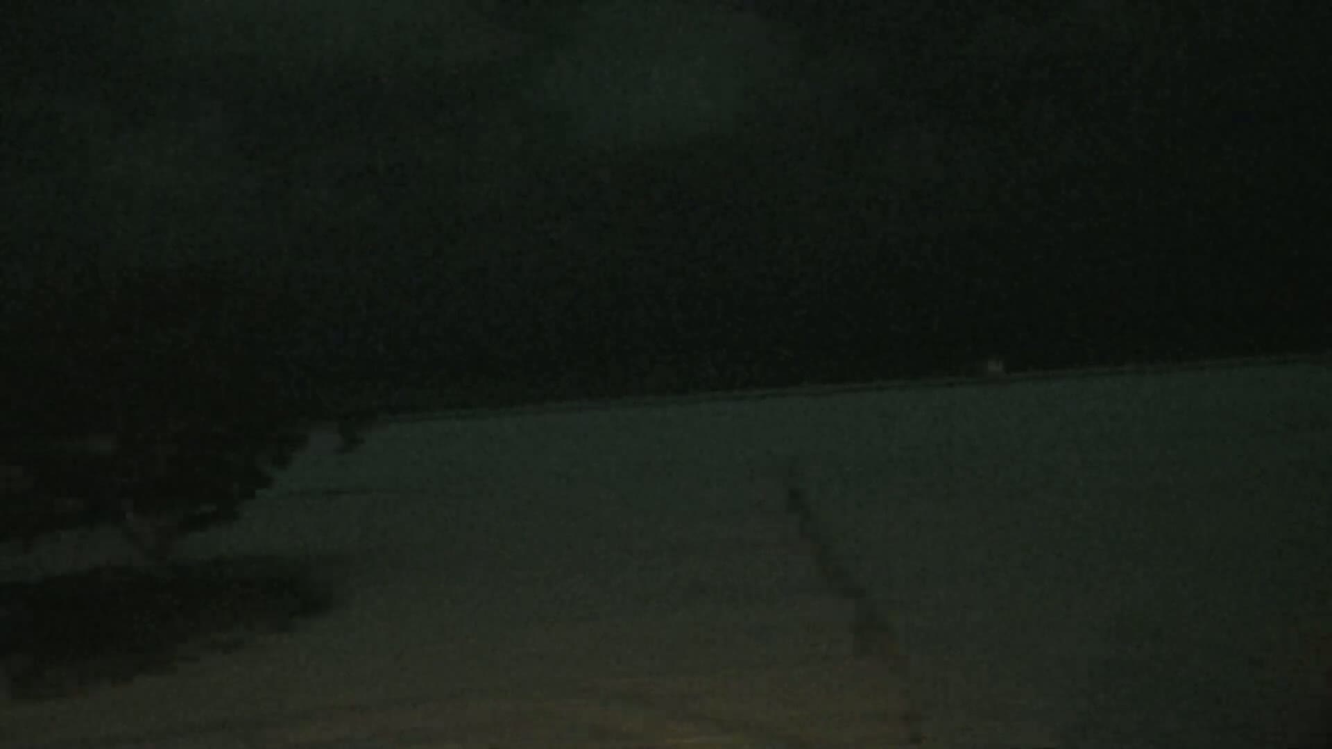 A dark, nighttime scene shows a flat, dark surface extending to the horizon under a cloudy sky.