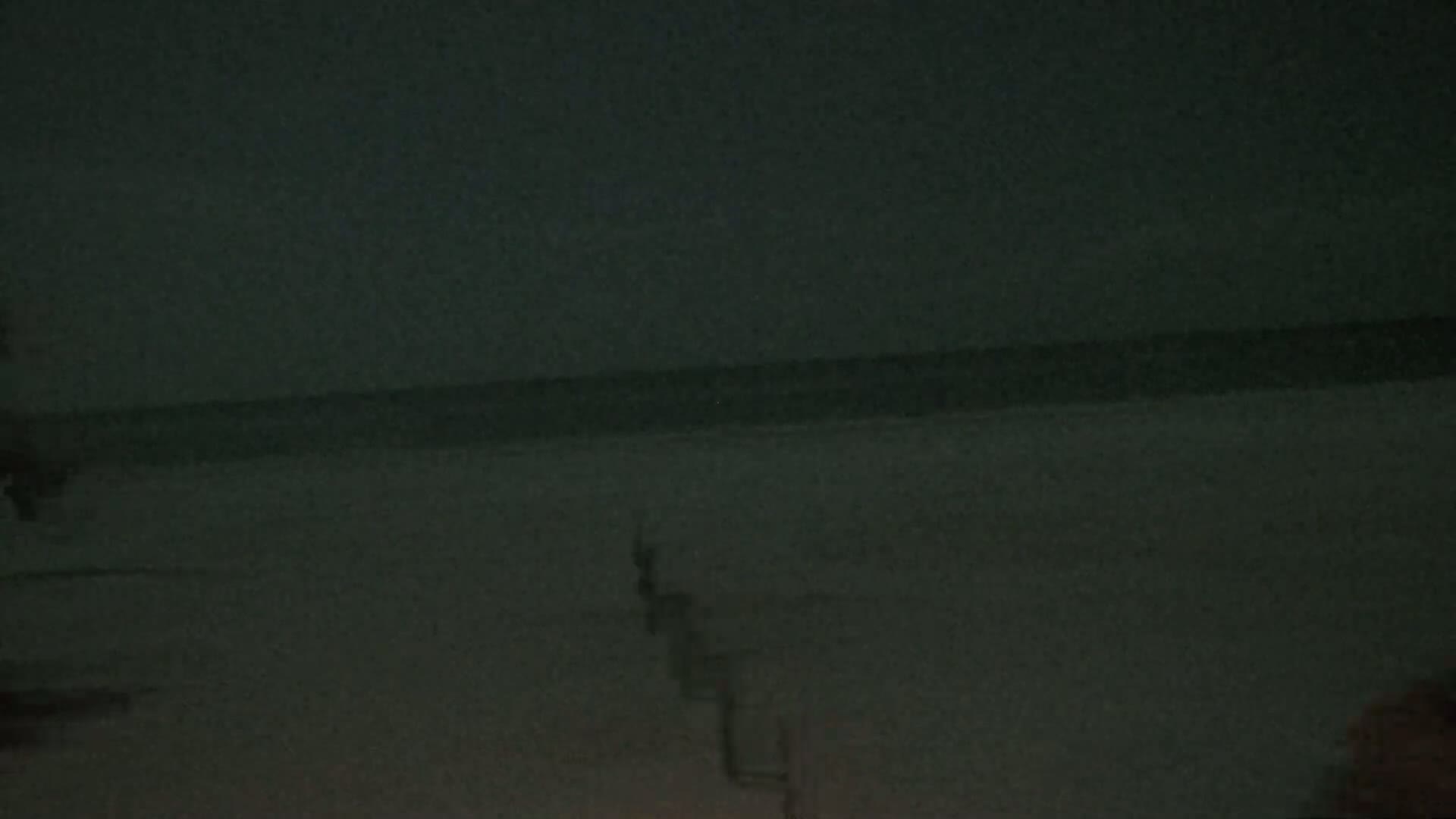 A dark, blurry image shows a body of water at night, possibly an ocean or lake, with a stairway or ladder-like structure descending towards it.
