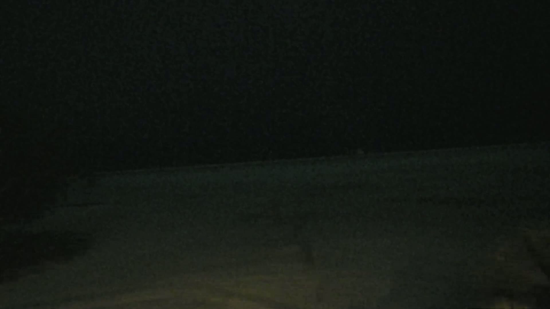 A dark, nighttime scene shows a flat, dark expanse of ground under a completely black sky.