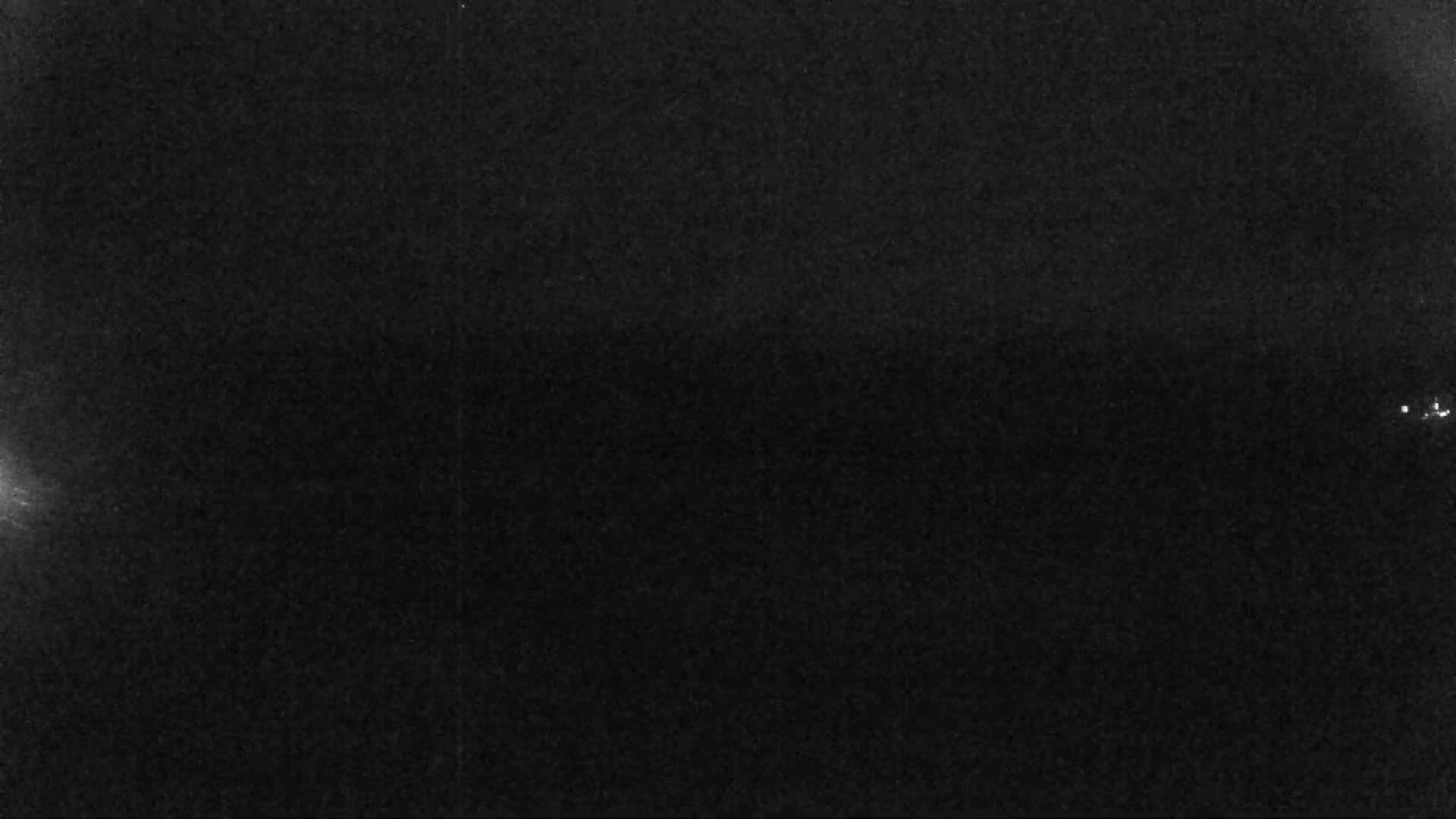 A dark, grainy image shows a mostly black sky with a few faint, distant lights.