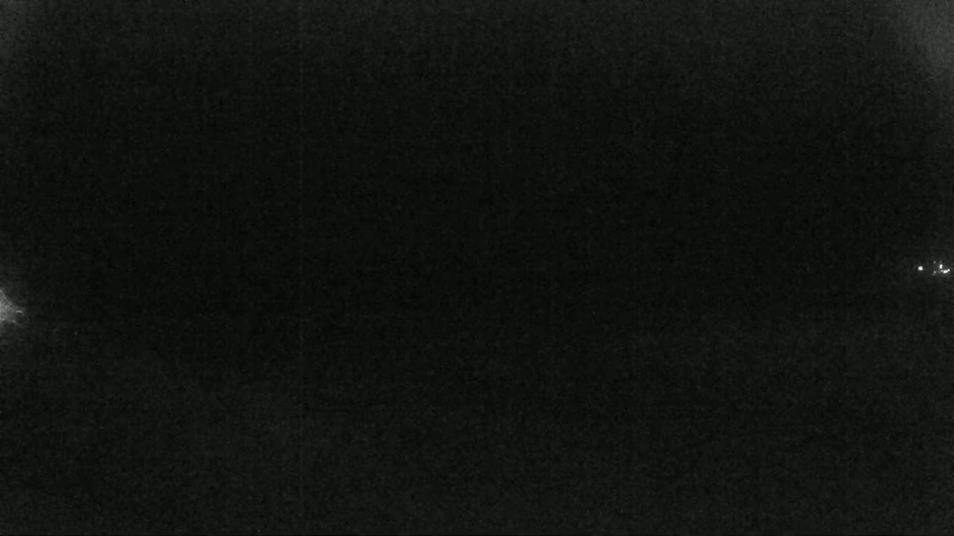 A mostly dark image shows a few small, faint lights against a predominantly black background at night.