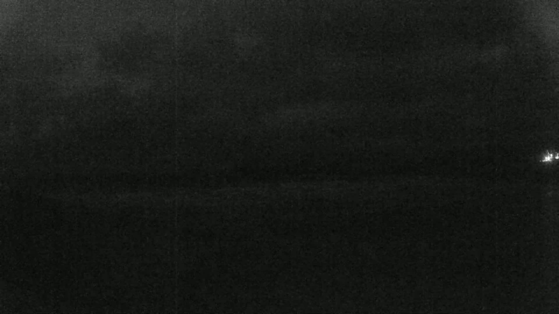 A dark, nighttime landscape is visible, with a faint, possibly cloudy sky overhead.