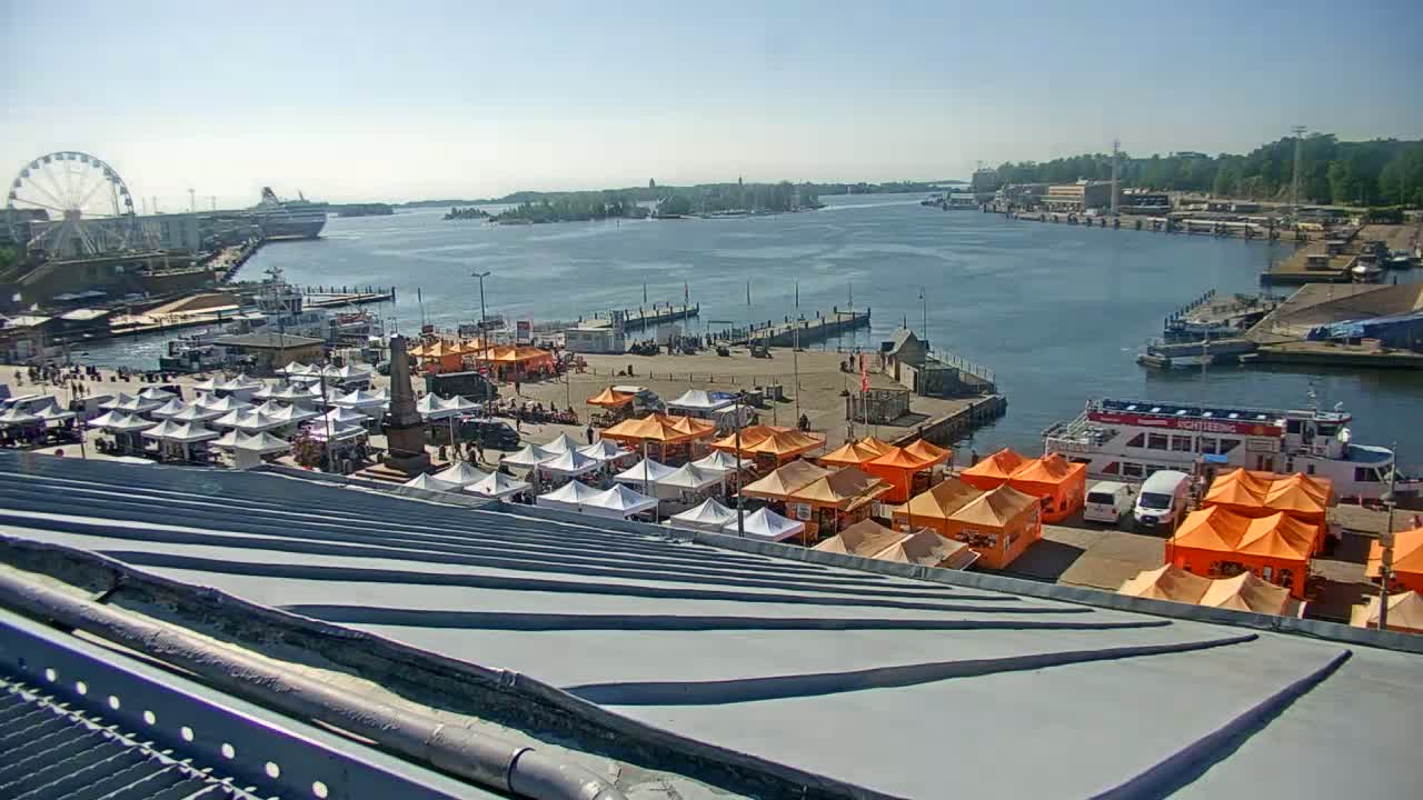 A harbor at twilight, with numerous orange tents and a large passenger boat docked, under a clear, dark sky.