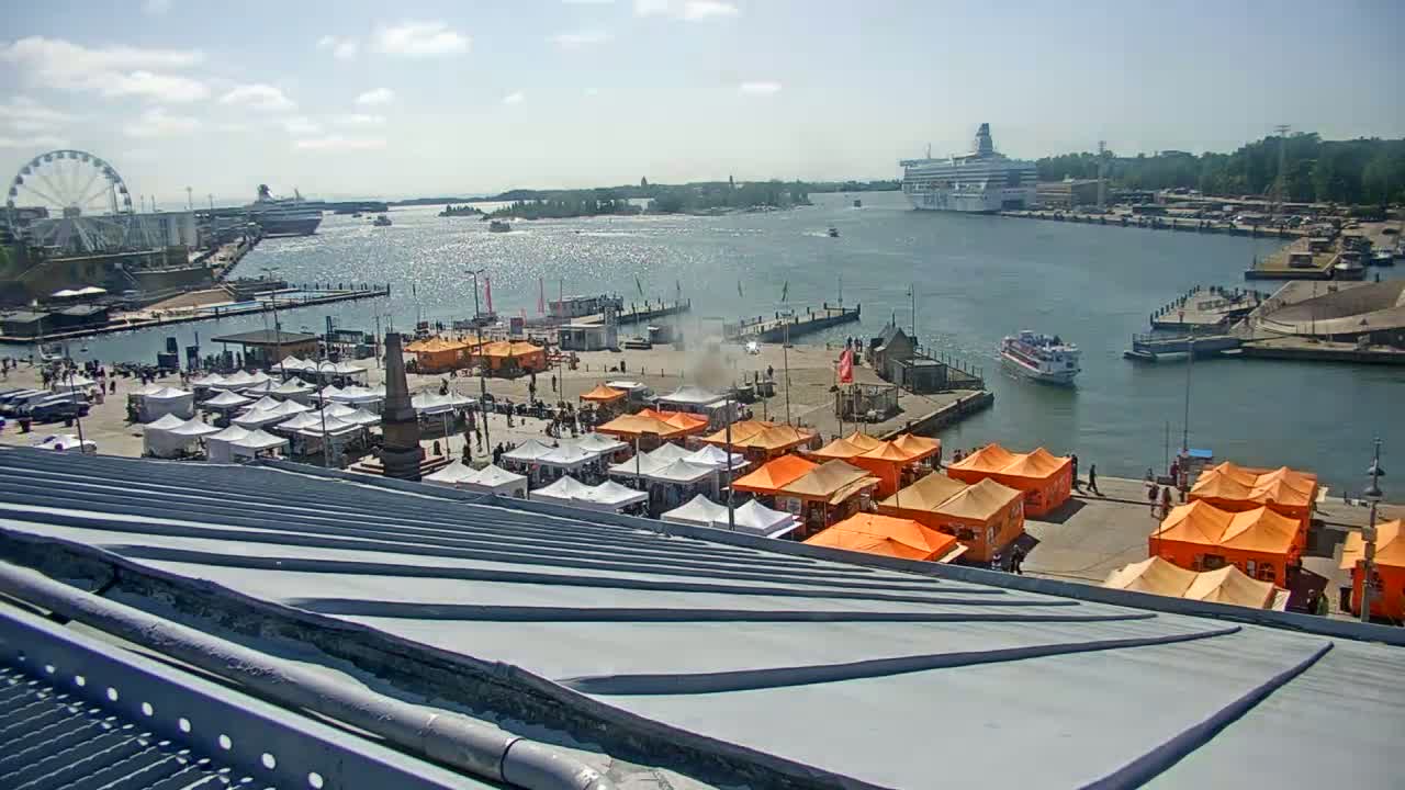 A sunny harbor scene shows numerous orange and white market stalls, a Ferris wheel, a large cruise ship, and boats on the water.