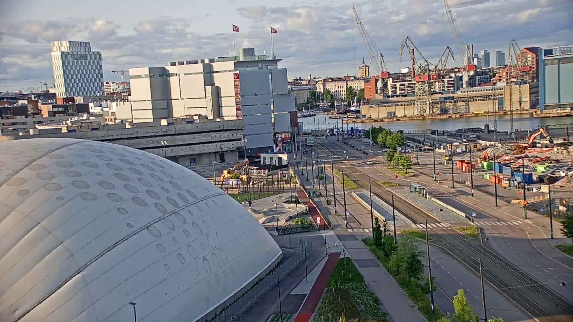 A mostly clear day shows a large domed building, urban landscape with several buildings and a body of water, and construction or demolition equipment in a shipyard area.
