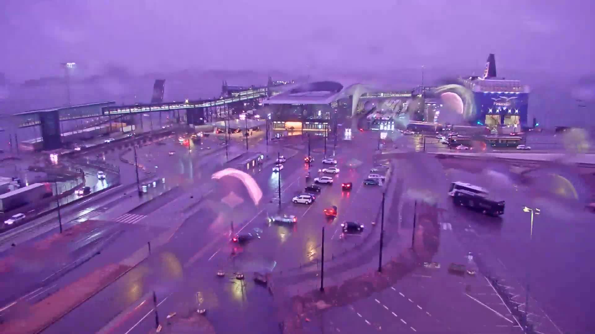 A ferry terminal and surrounding roads are flooded under a purple-tinged stormy sky.