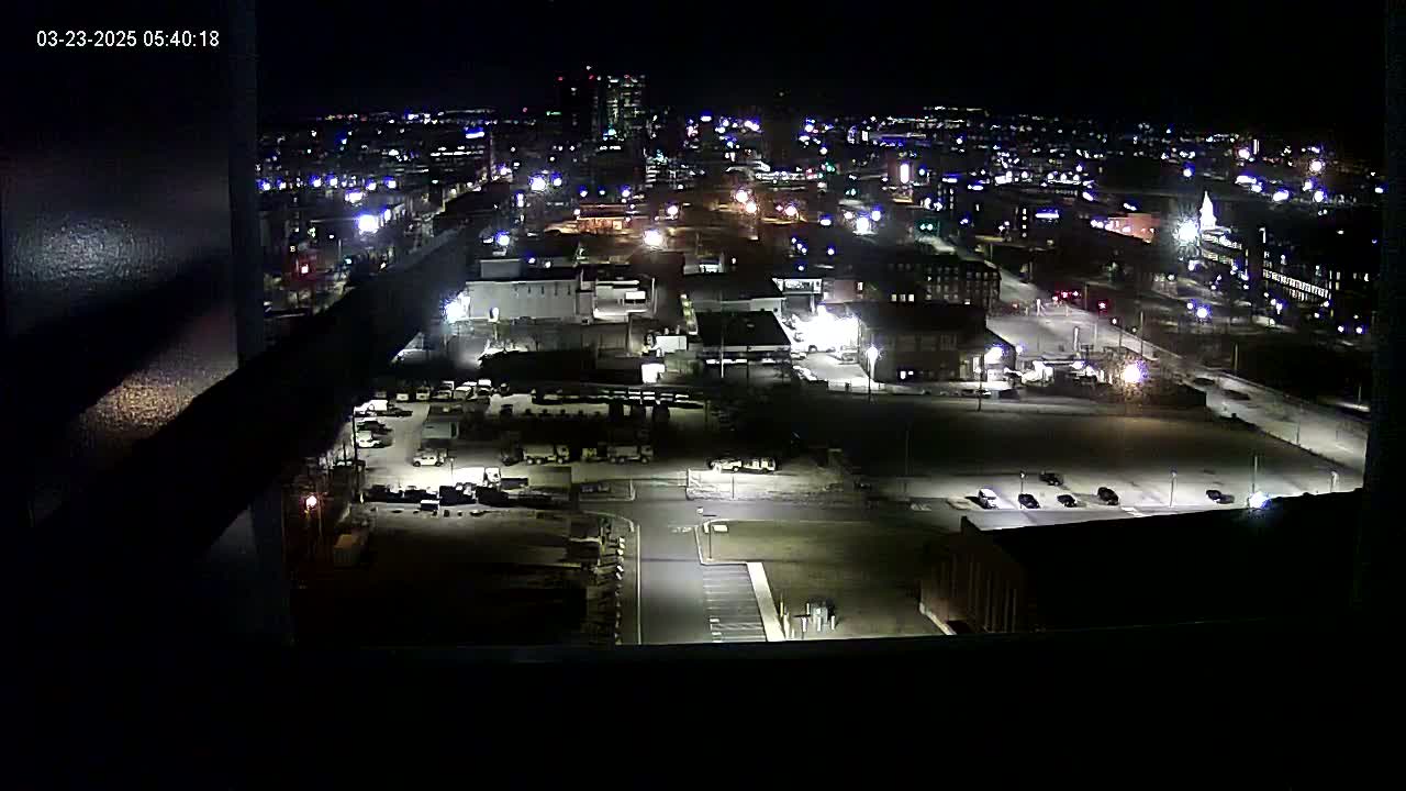 A nighttime aerial view of an industrial area with sparsely lit parking lots and buildings, under a clear sky.