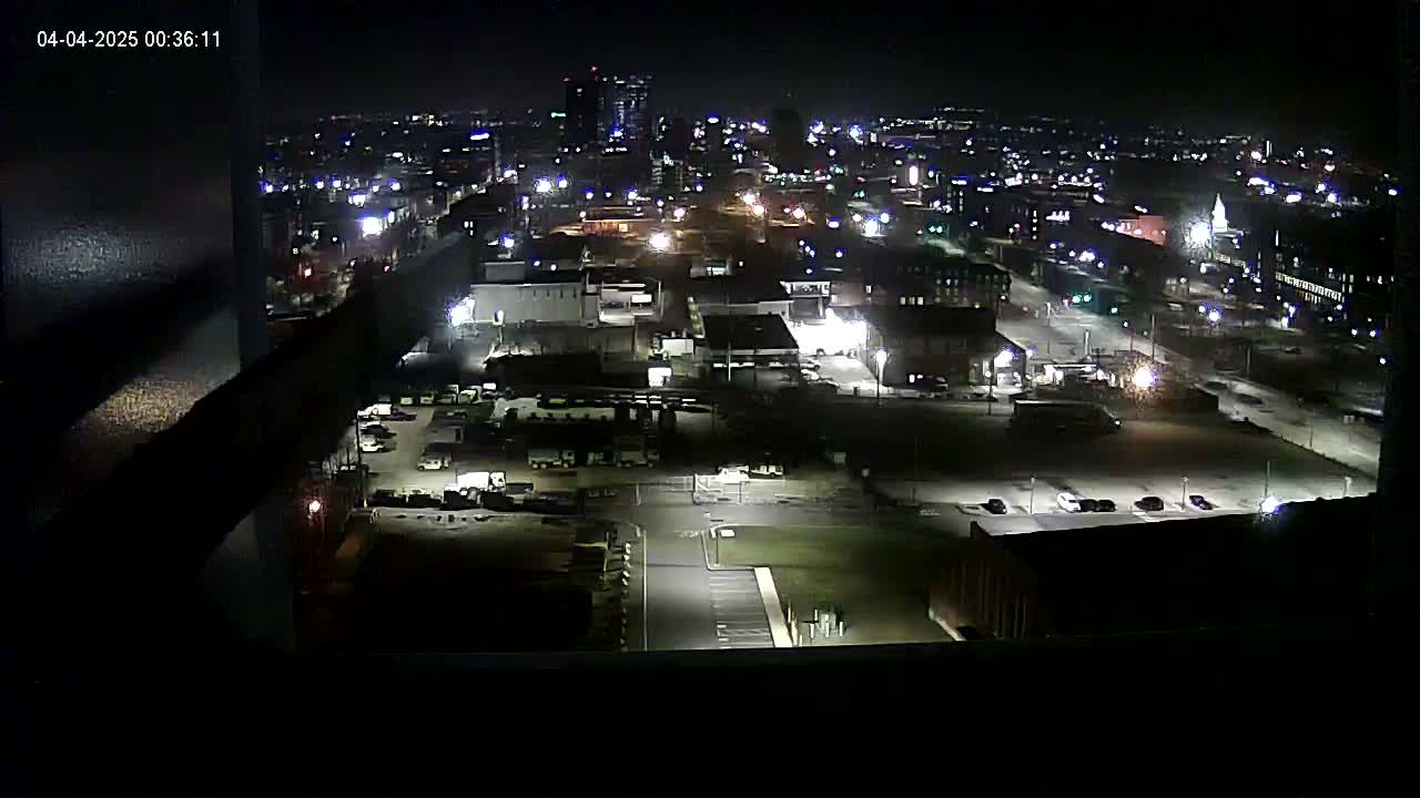 A nighttime, high-angle view of a city's industrial area with several buildings and parking lots illuminated by artificial lights.