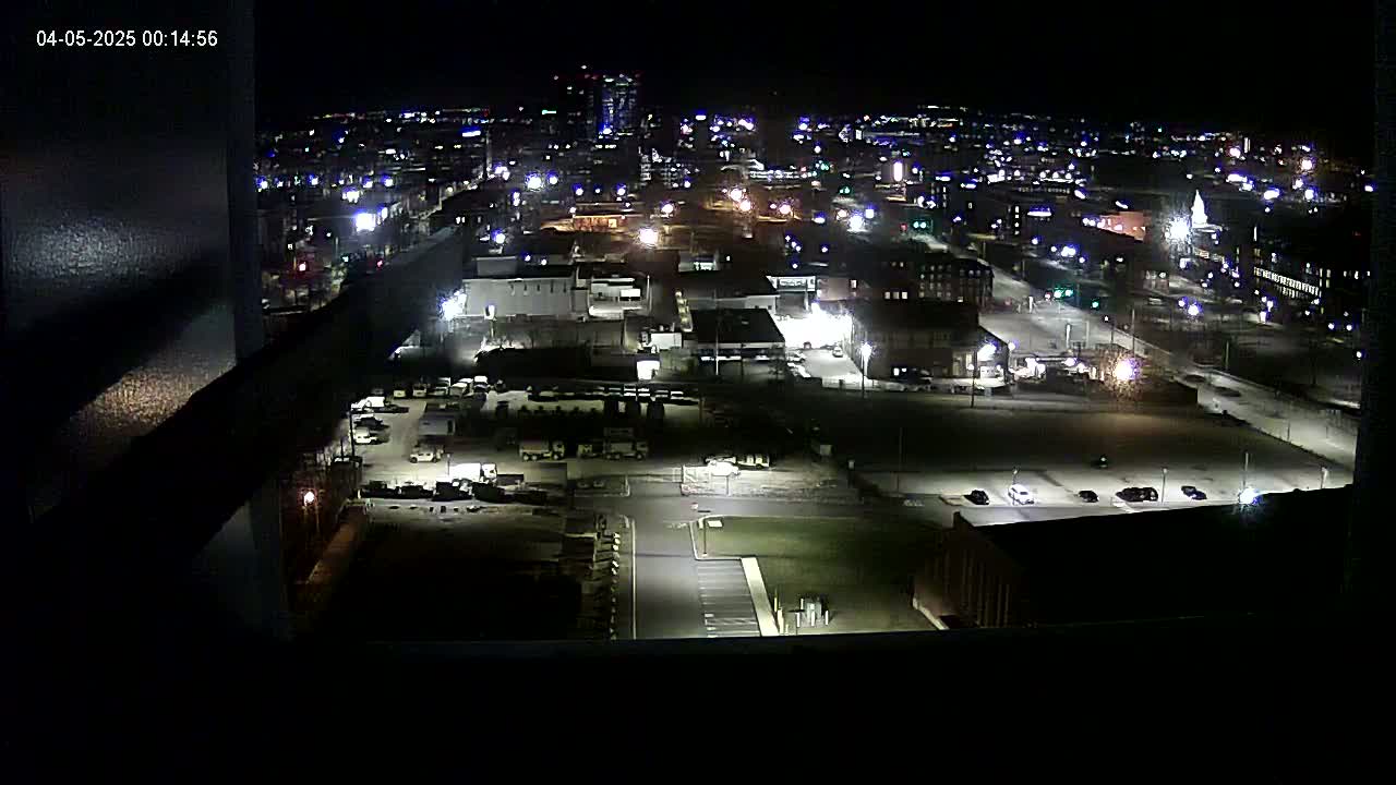 A nighttime, high-angle view of a city's industrial and residential areas, illuminated by artificial lights.