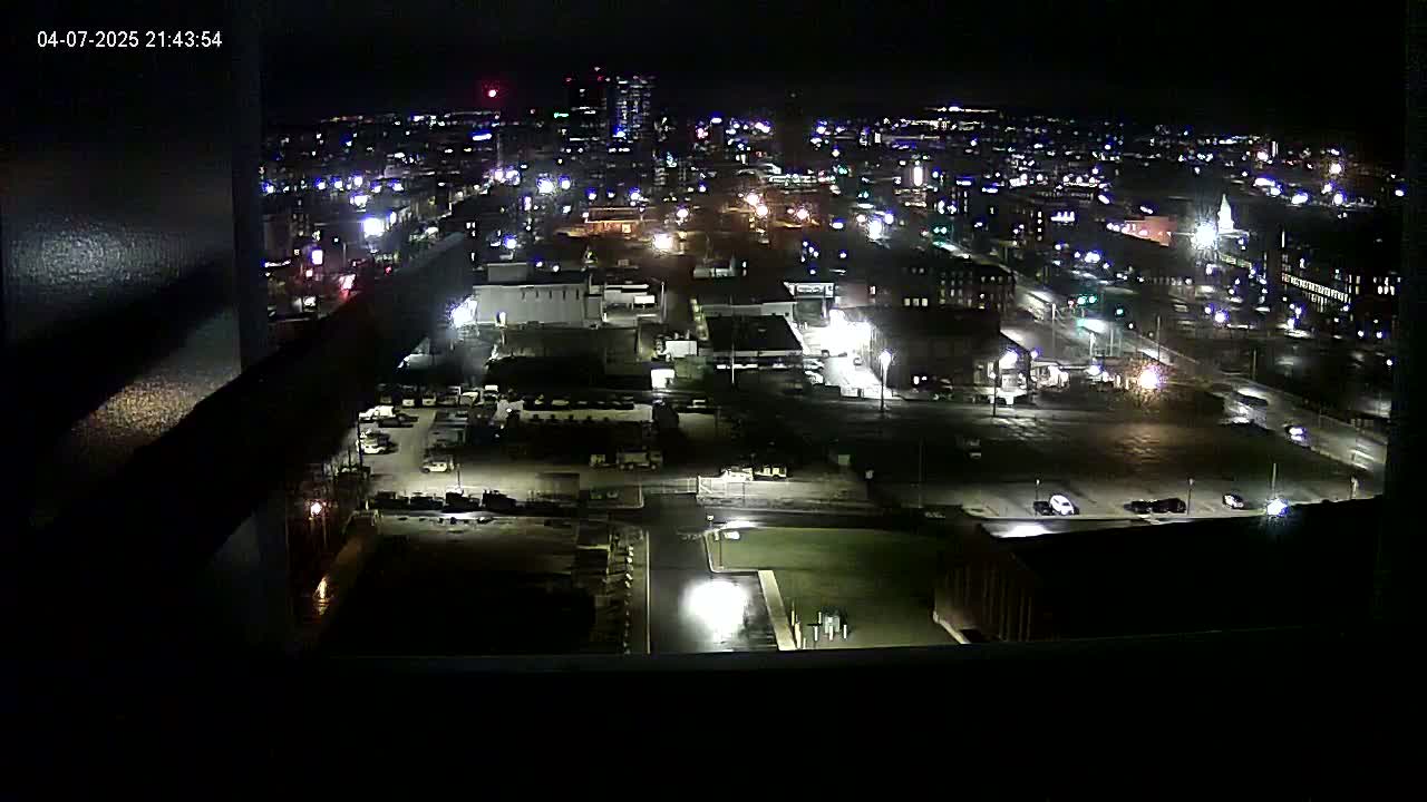 A nighttime, high-angle view of a city illuminated by streetlights and building lights.