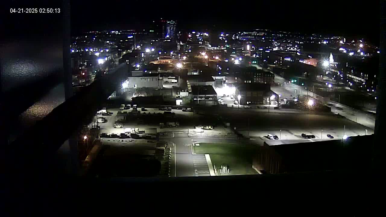 A nighttime aerial view of a city's industrial area, with dimly lit streets, parking lots, and buildings.