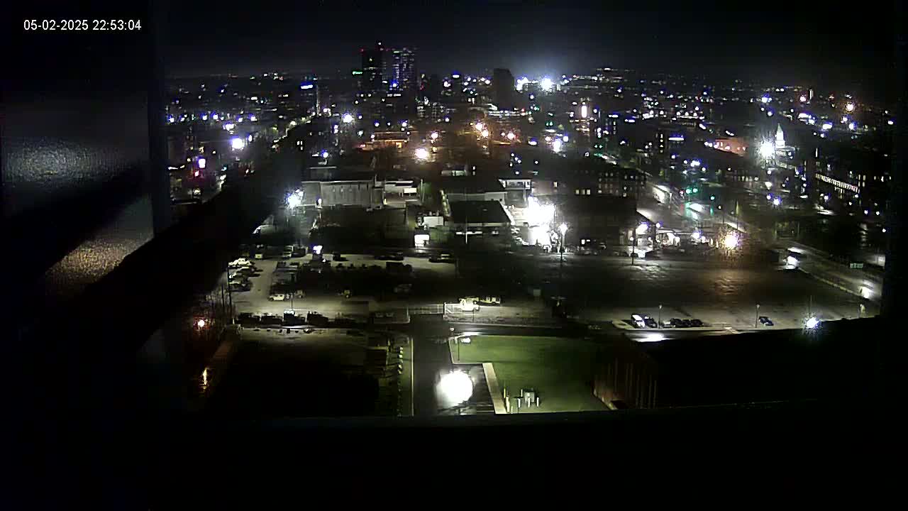 A nighttime, high-angle view of a city illuminated by streetlights and building lights, showing a mix of industrial and residential areas.