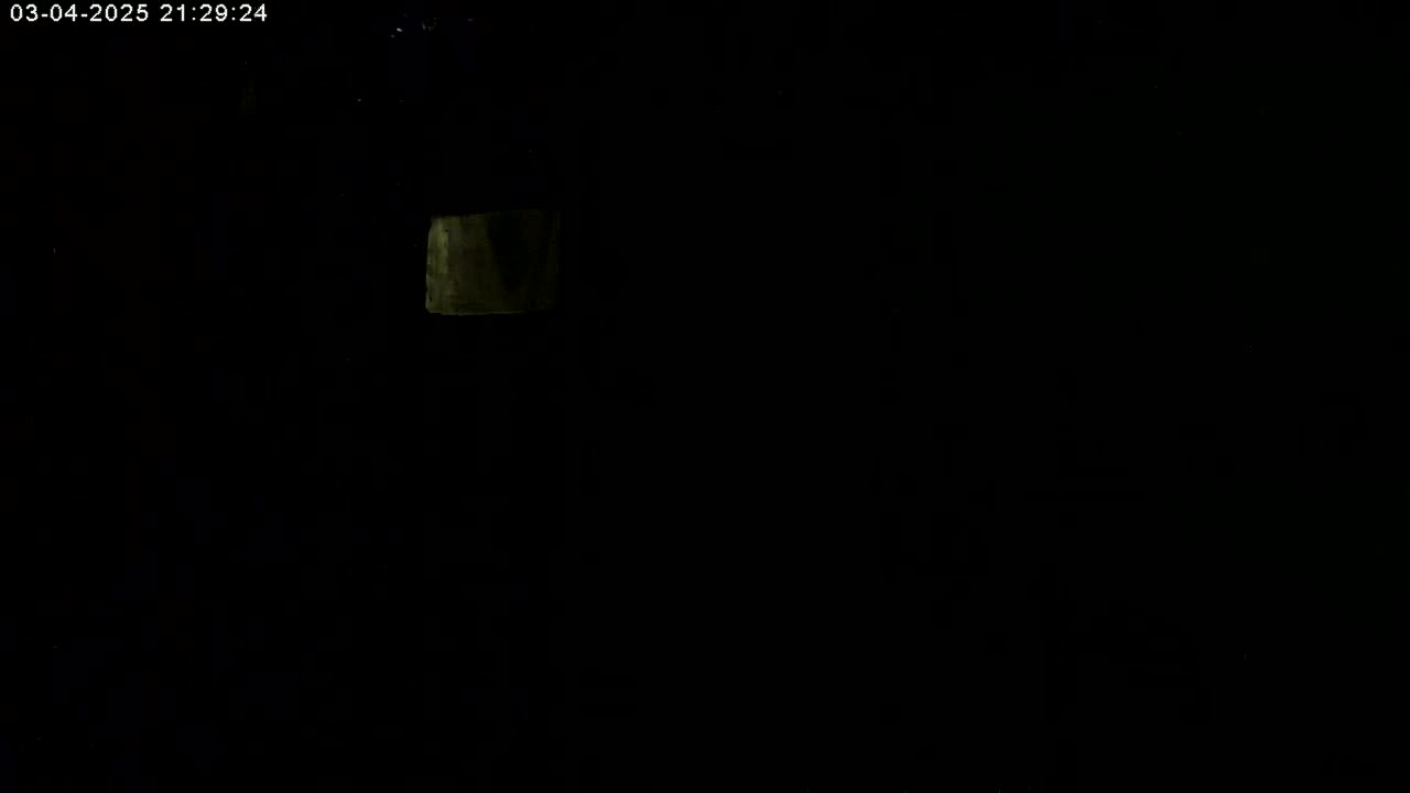 A dimly lit, dark scene shows a small, square light source in the upper left corner.