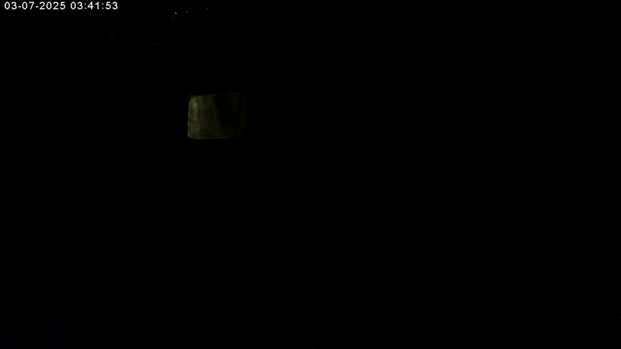 A dimly lit, dark scene shows a small, faintly illuminated rectangle in the upper left corner.