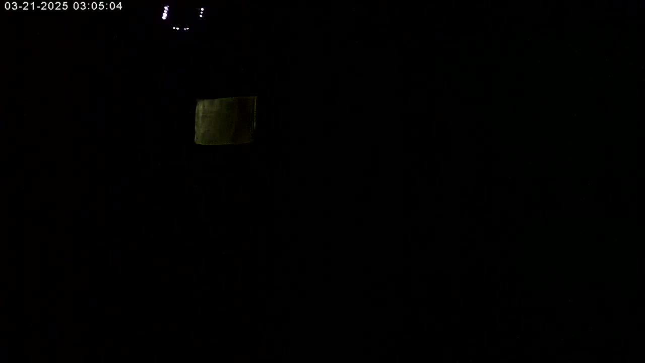 A dark, nighttime scene shows a faintly illuminated, rectangular object in the upper left.