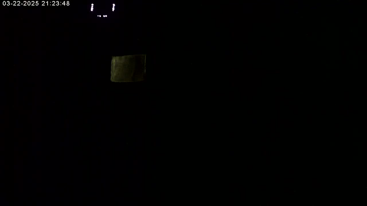 A dimly lit, dark scene shows a small, faintly illuminated rectangular object in the upper-center.