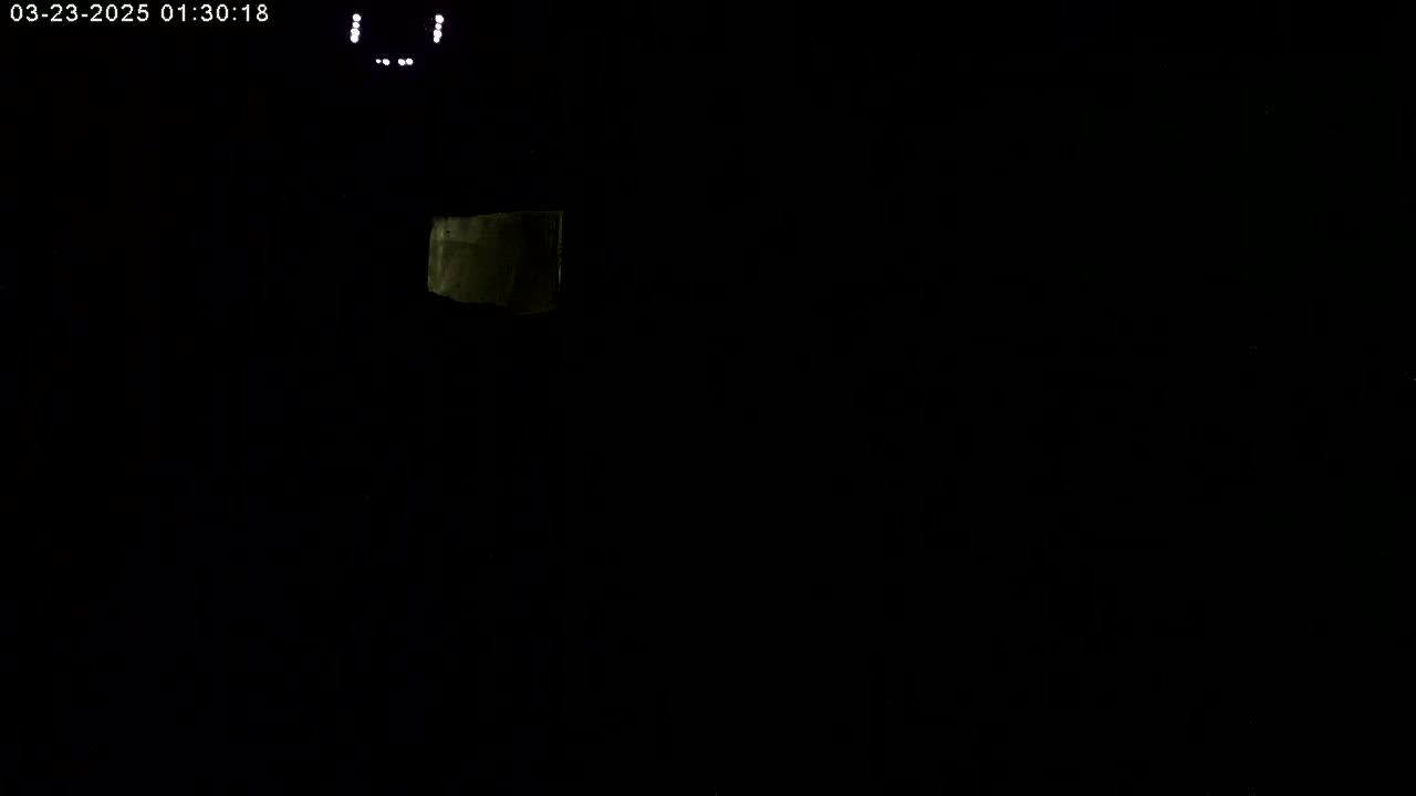 A dimly lit, mostly dark scene shows a small, faintly illuminated object in the upper left corner.