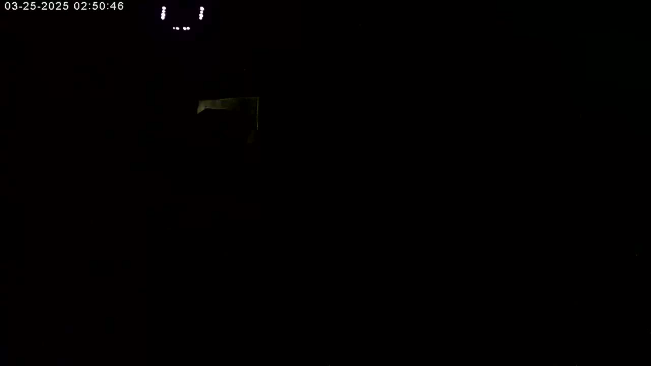 A dimly lit, mostly dark scene shows a small, pale rectangular object in the upper center.