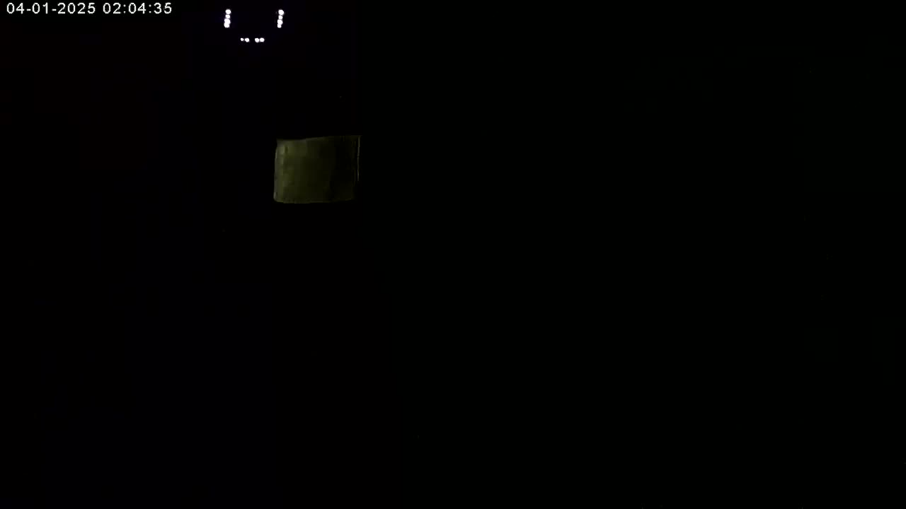 A dimly lit, dark scene shows a small, pale rectangle in the upper left corner.