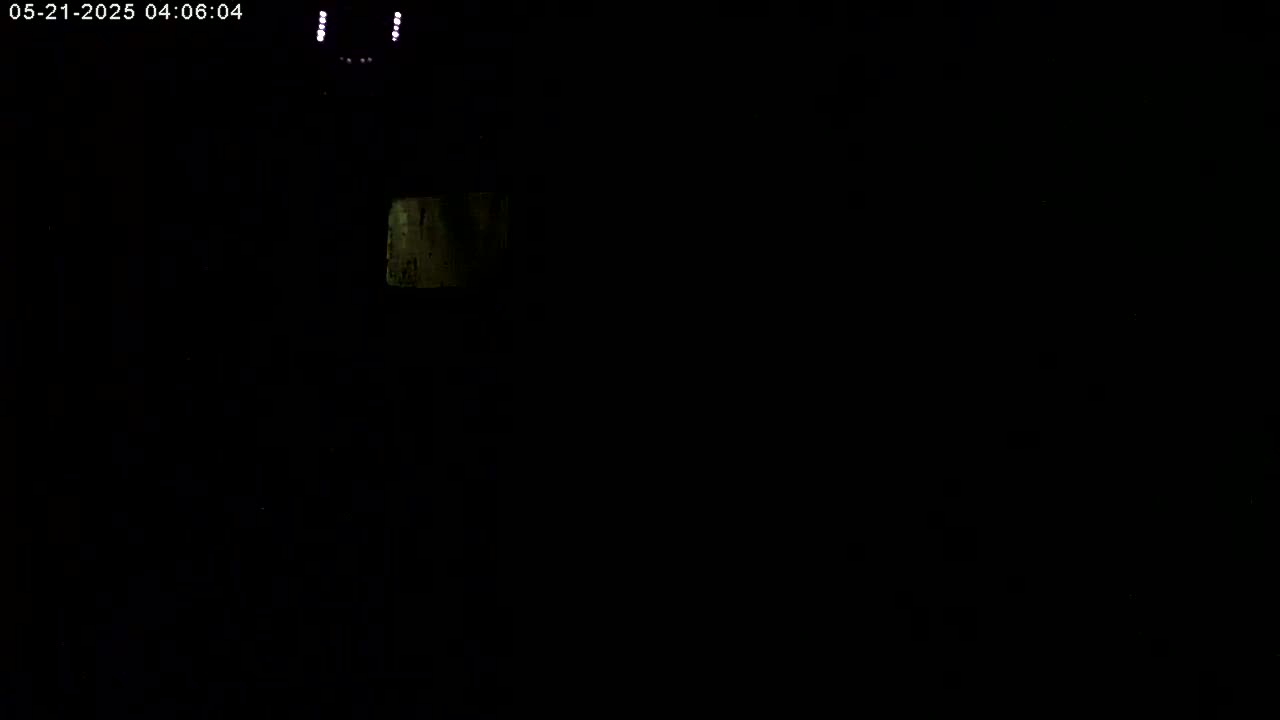 A dimly lit, dark space shows a small, faintly illuminated rectangular object in the upper left quadrant.
