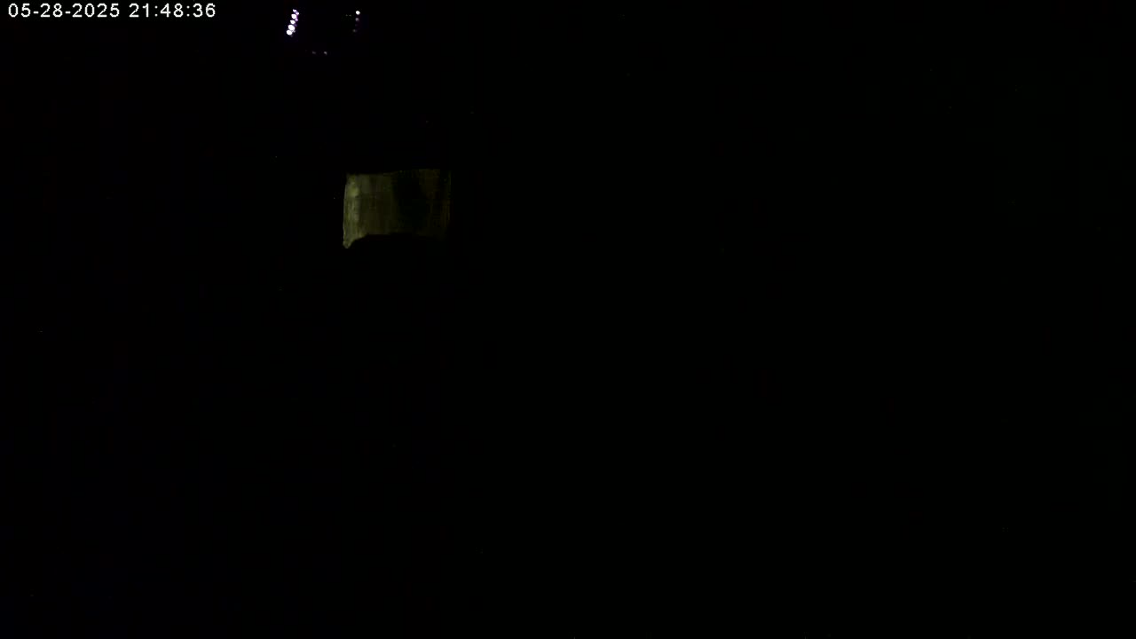 A mostly dark image shows a small, faintly illuminated rectangular object in the upper left corner.